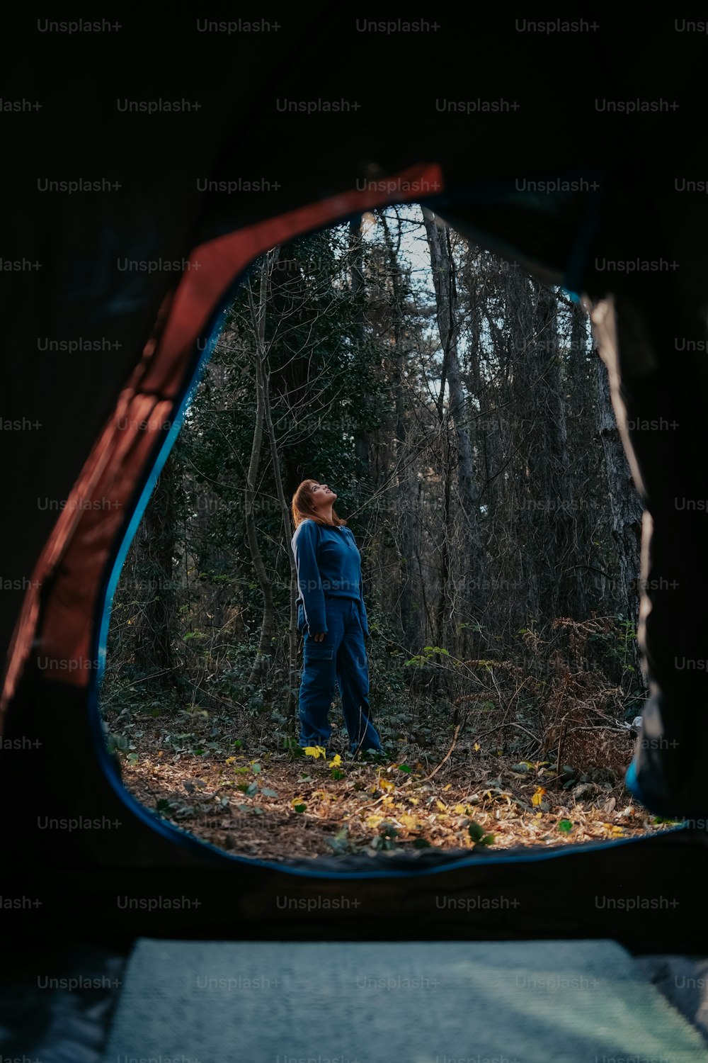 a man in a blue jumpsuit standing in the woods