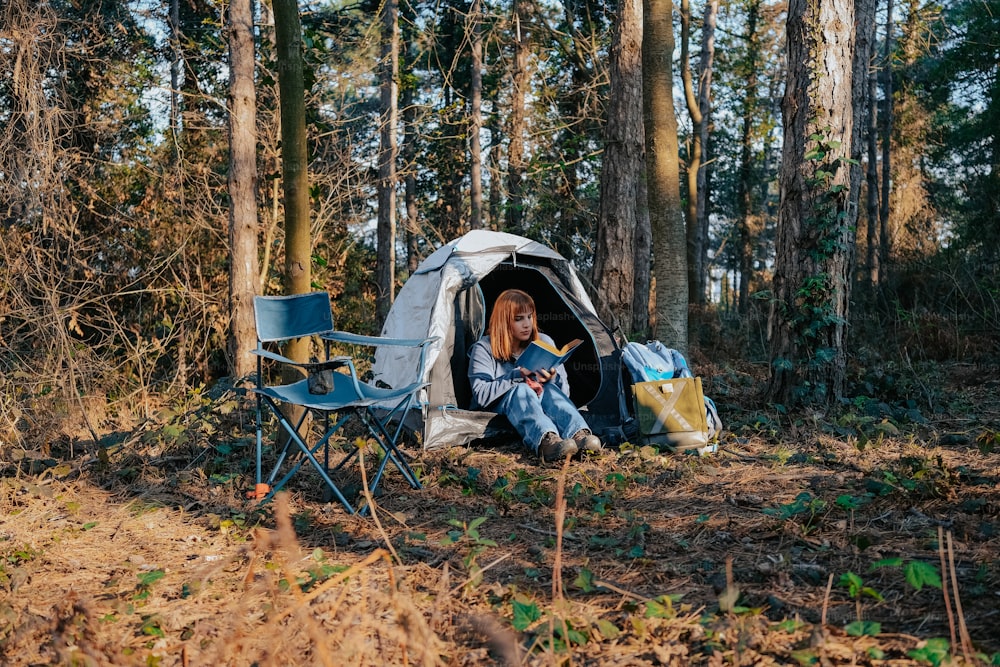 a woman sitting in a tent reading a book