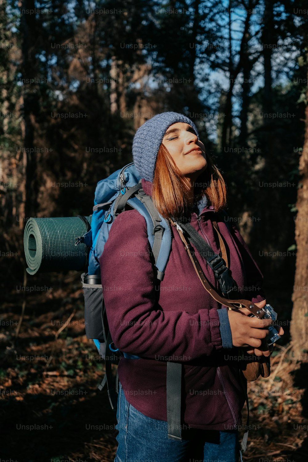 a woman with a backpack is standing in the woods