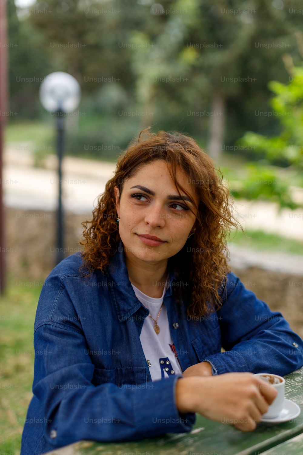 a woman sitting at a table with a cup of coffee