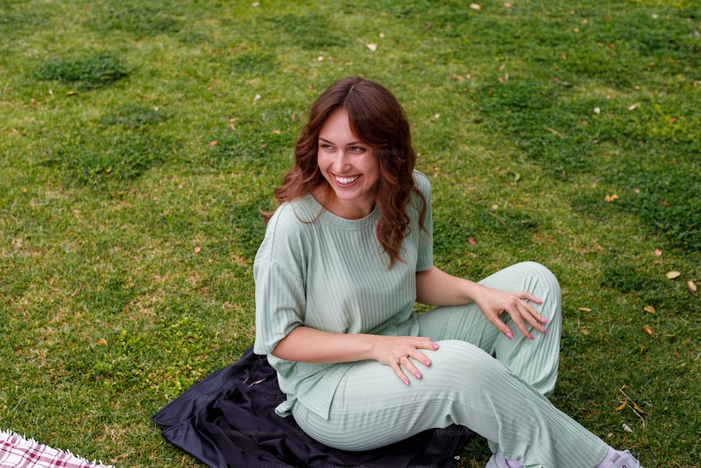 uma mulher está sentada na grama sorrindo