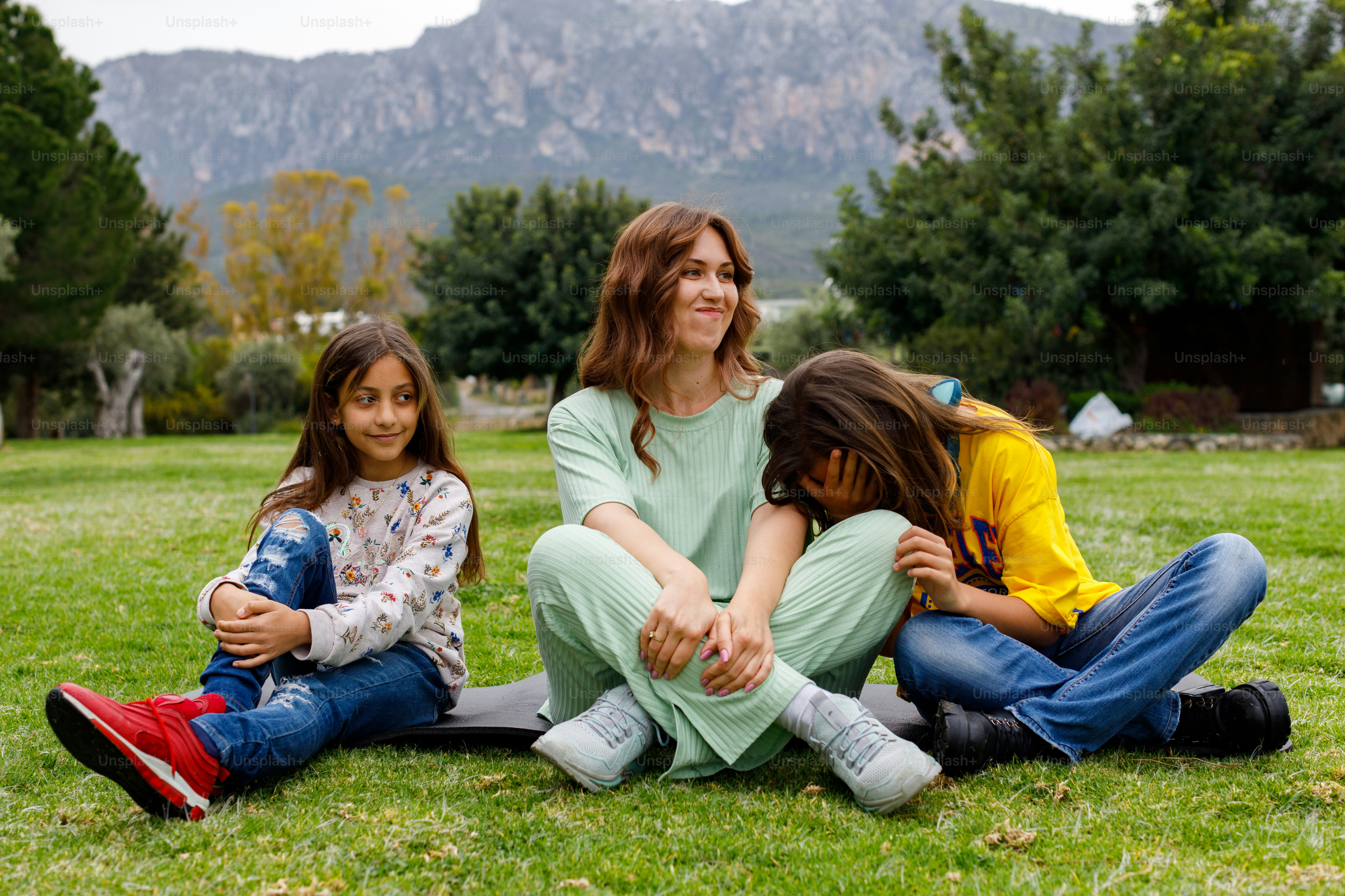 a woman sitting on the ground with two children