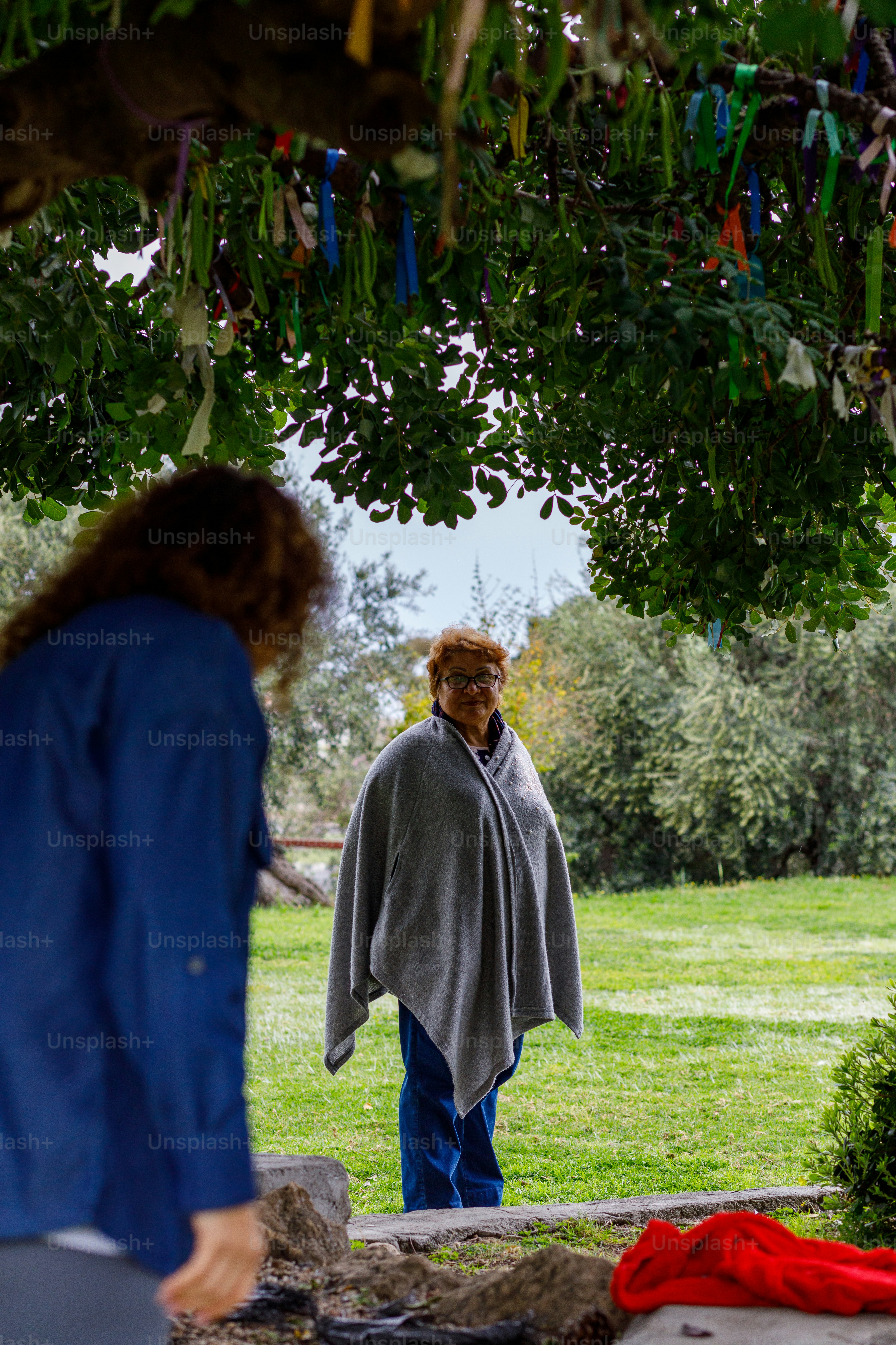 a woman standing under a tree next to a man