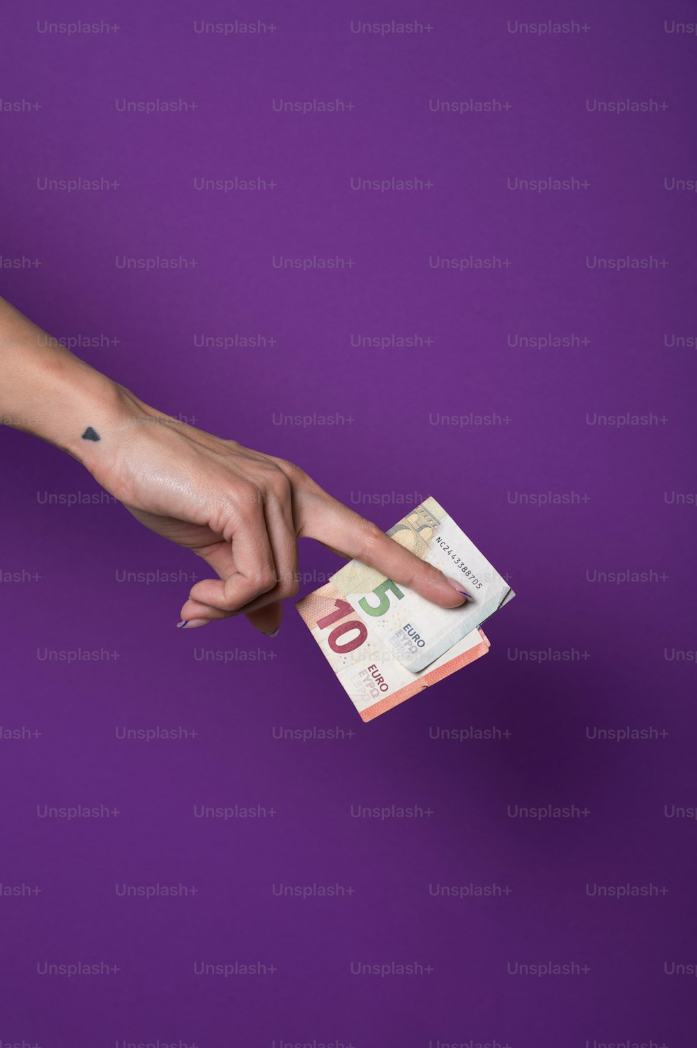 a mão de uma mulher apontando para uma pilha de dinheiro