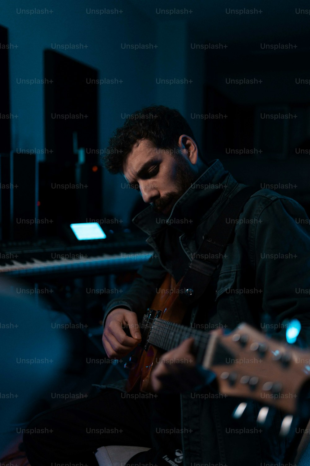 a man playing a guitar in front of a keyboard
