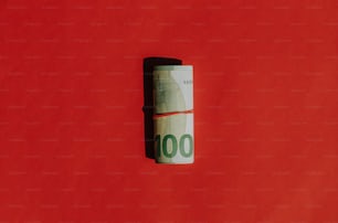 a roll of hundred dollar bills on a red background