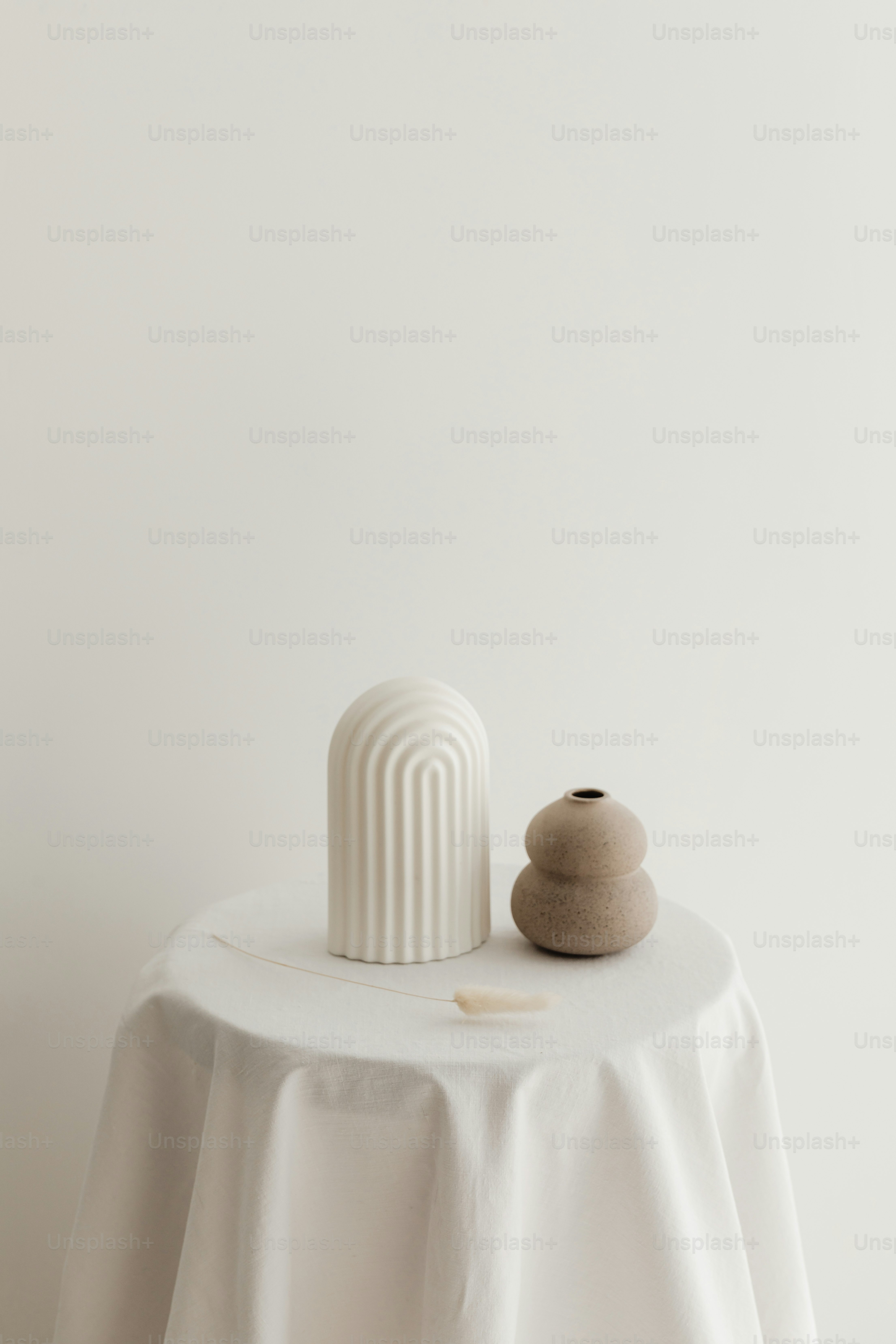 a white table topped with a white vase and a white table cloth