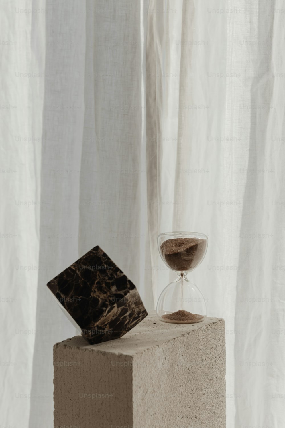 an hourglass sitting on top of a block of concrete