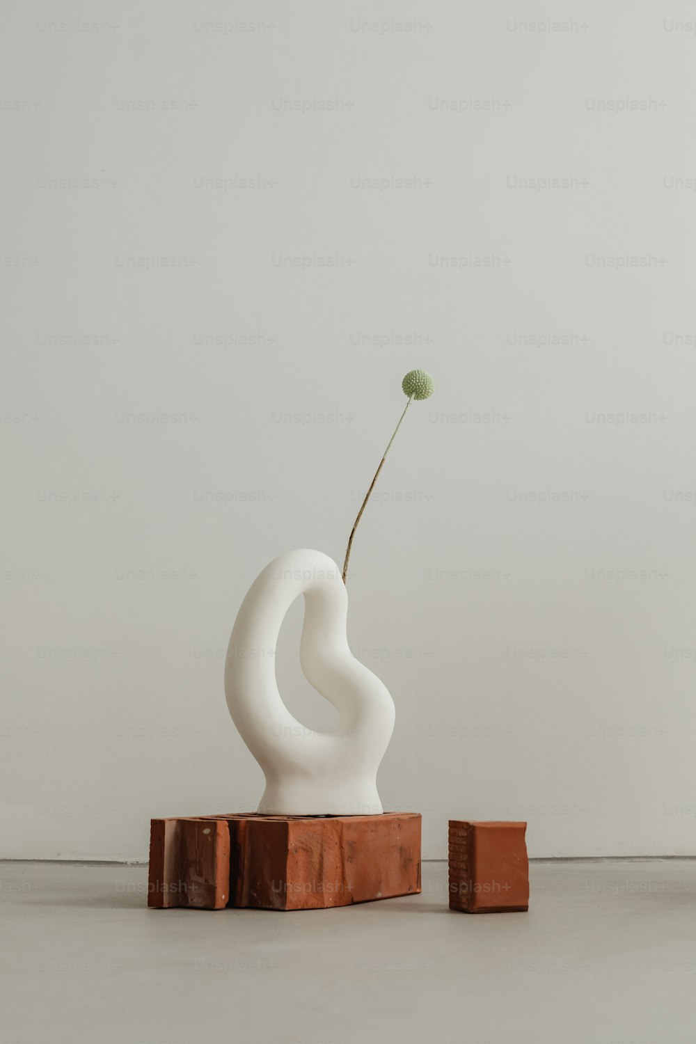 a white sculpture with a single flower in it