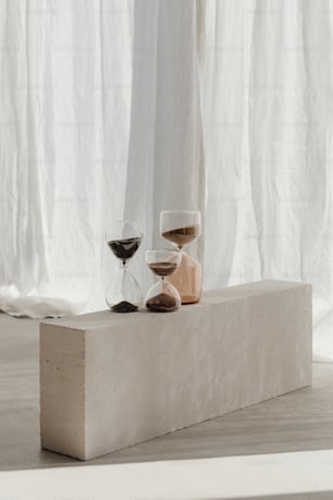 a couple of wine glasses sitting on top of a block of concrete