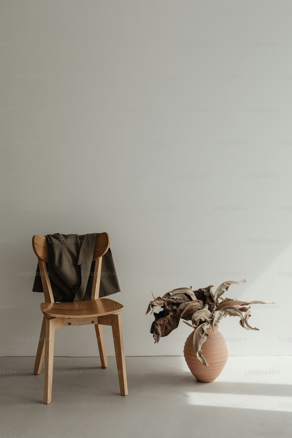 a chair next to a vase with a plant in it