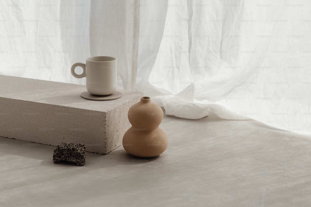 a vase and a cup sitting on a ledge