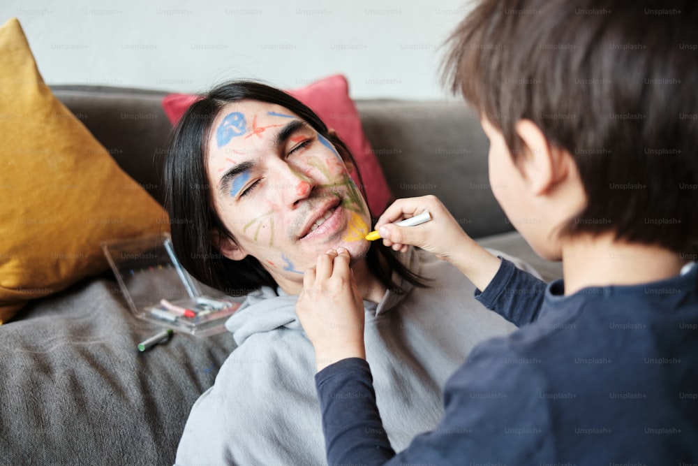 a woman getting her face painted by a young boy