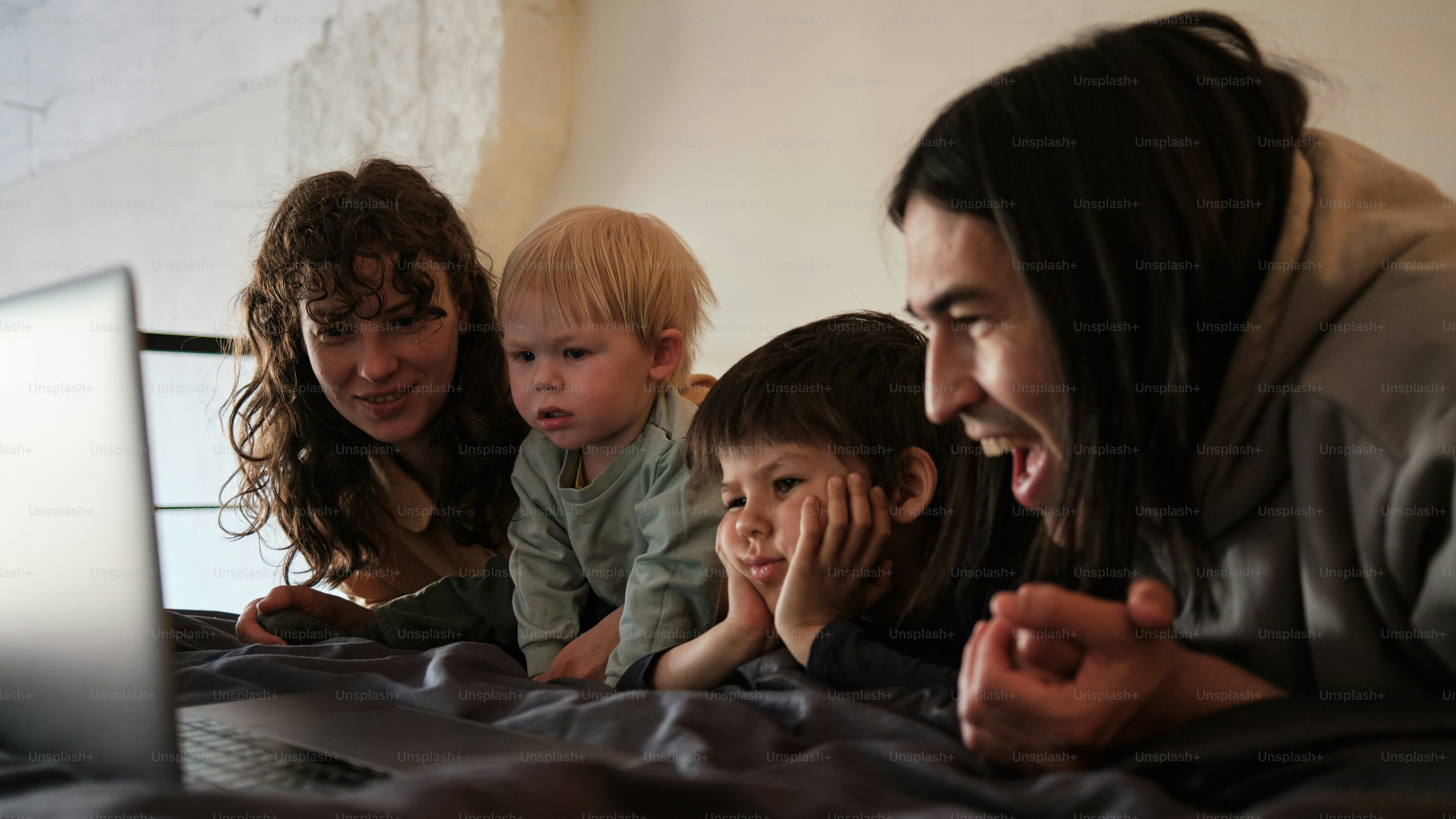 Un grupo de personas acostadas en una cama junto a una computadora portátil
