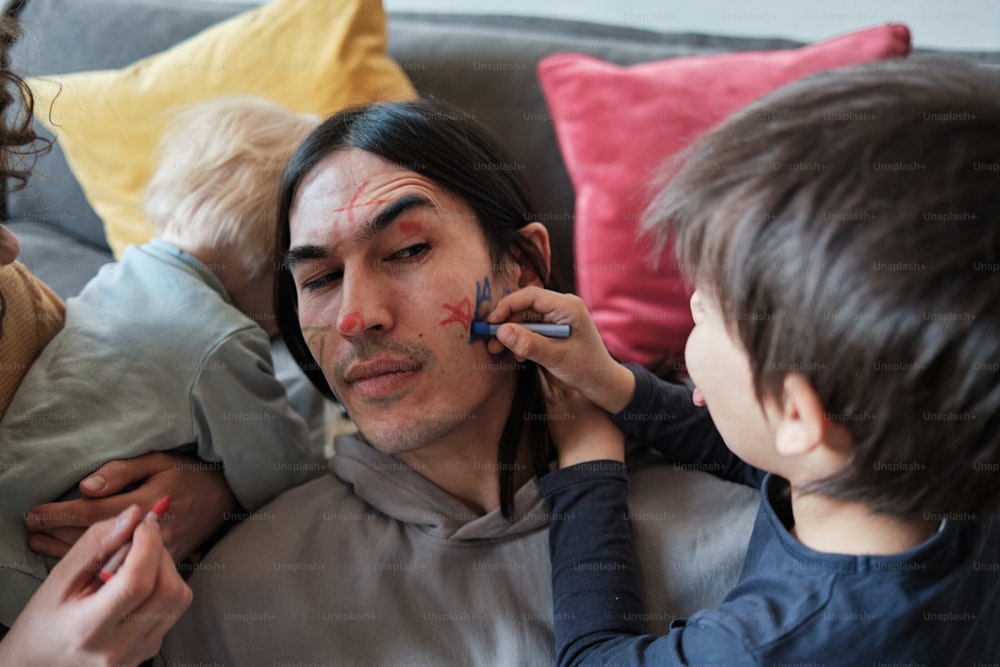 a man with a face paint on his face is being assisted by two children