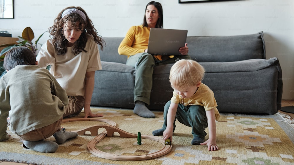 a woman and two children playing with a train set