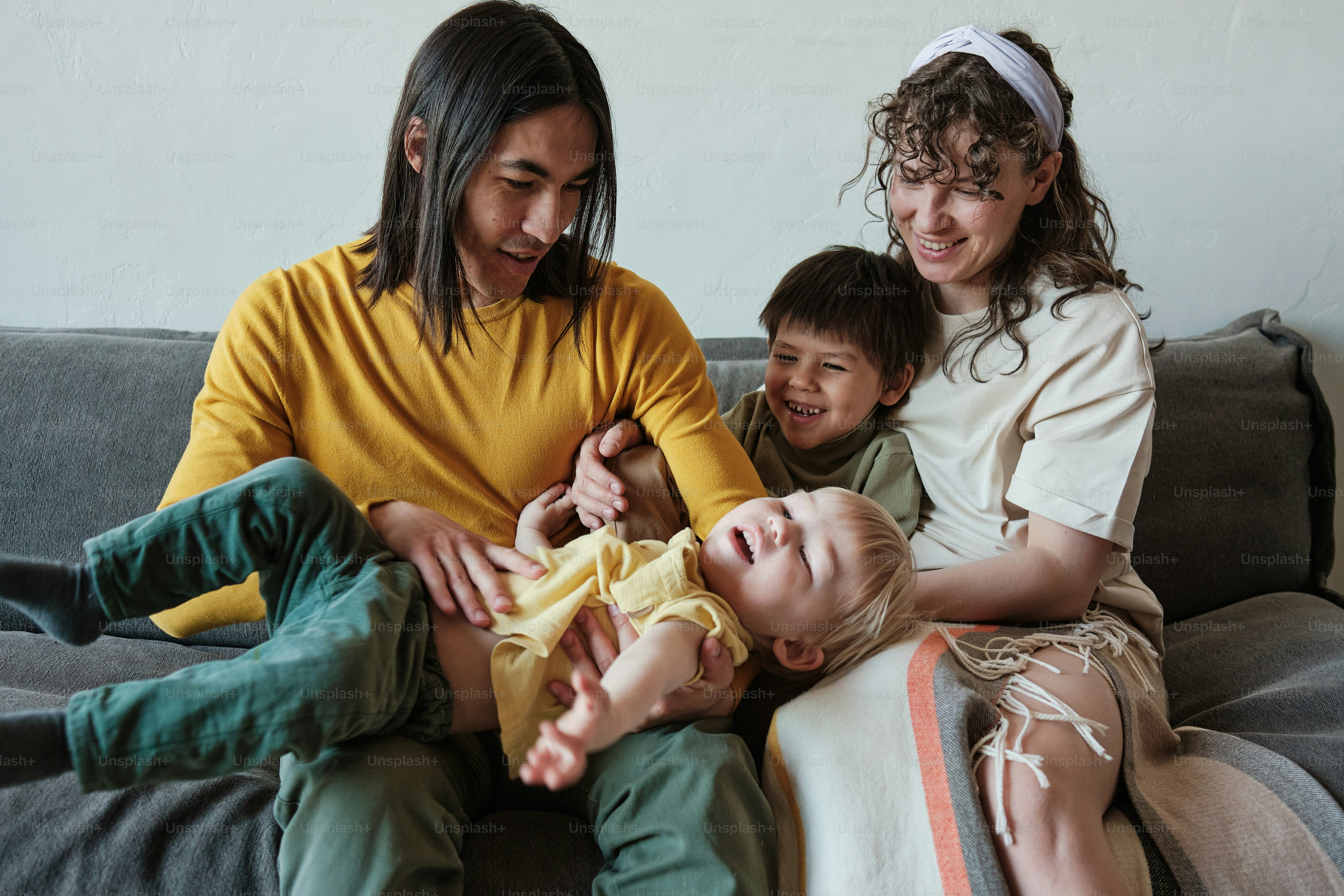 Eine dreiköpfige Familie sitzt zusammen auf einer Couch