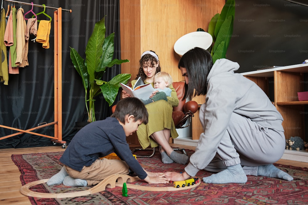 Una mujer y dos niños jugando con un tren de juguete