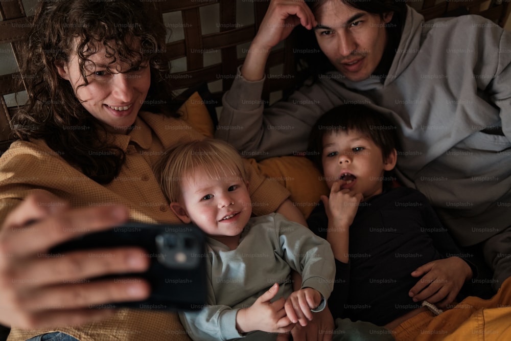 a woman taking a picture of a family with a cell phone