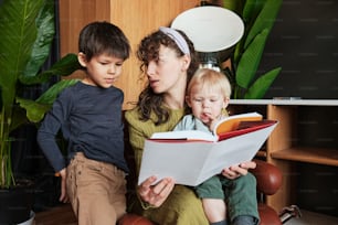 uma mulher lendo um livro para duas crianças