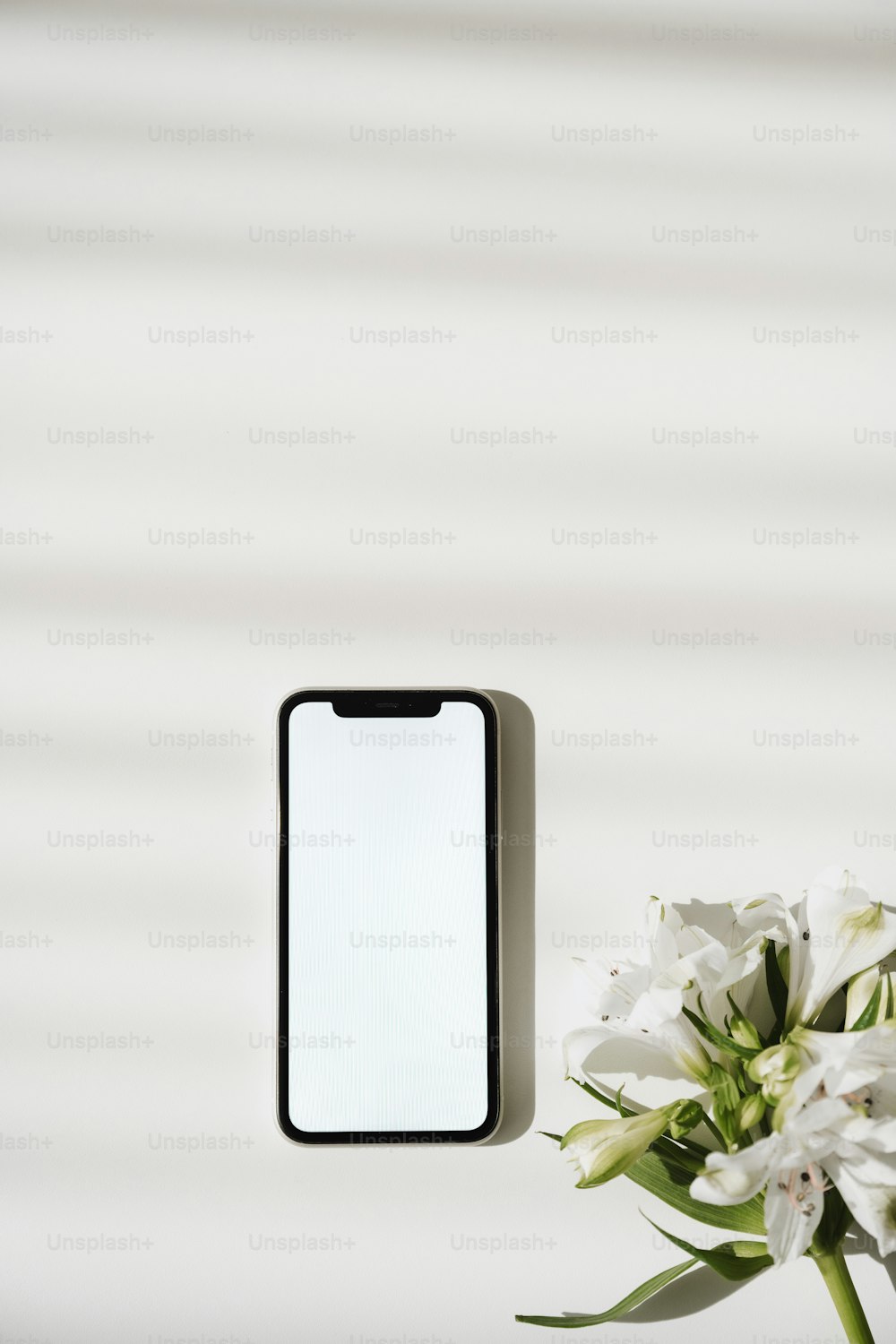 a vase with flowers and a cell phone on a table