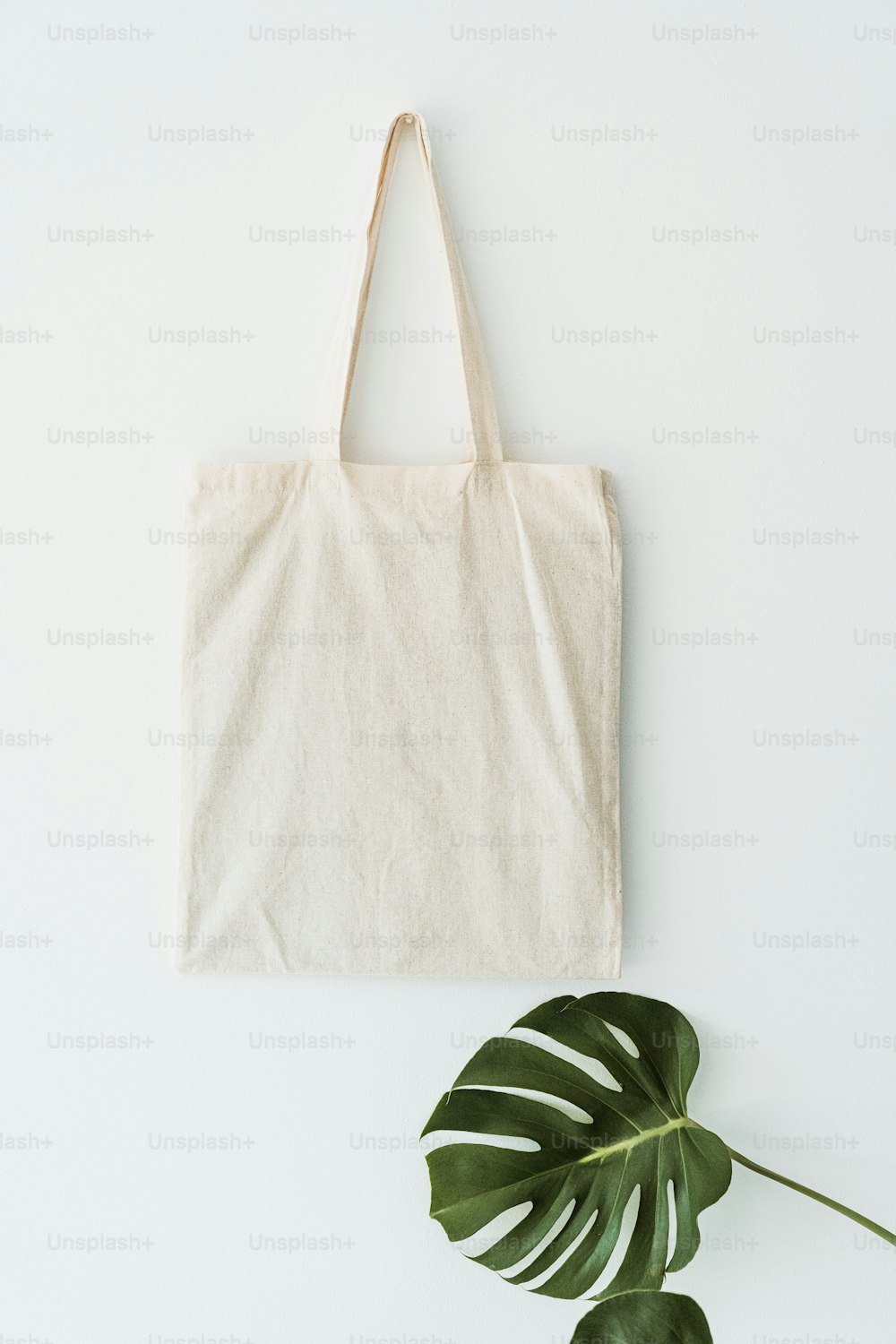 a white tote bag next to a green plant