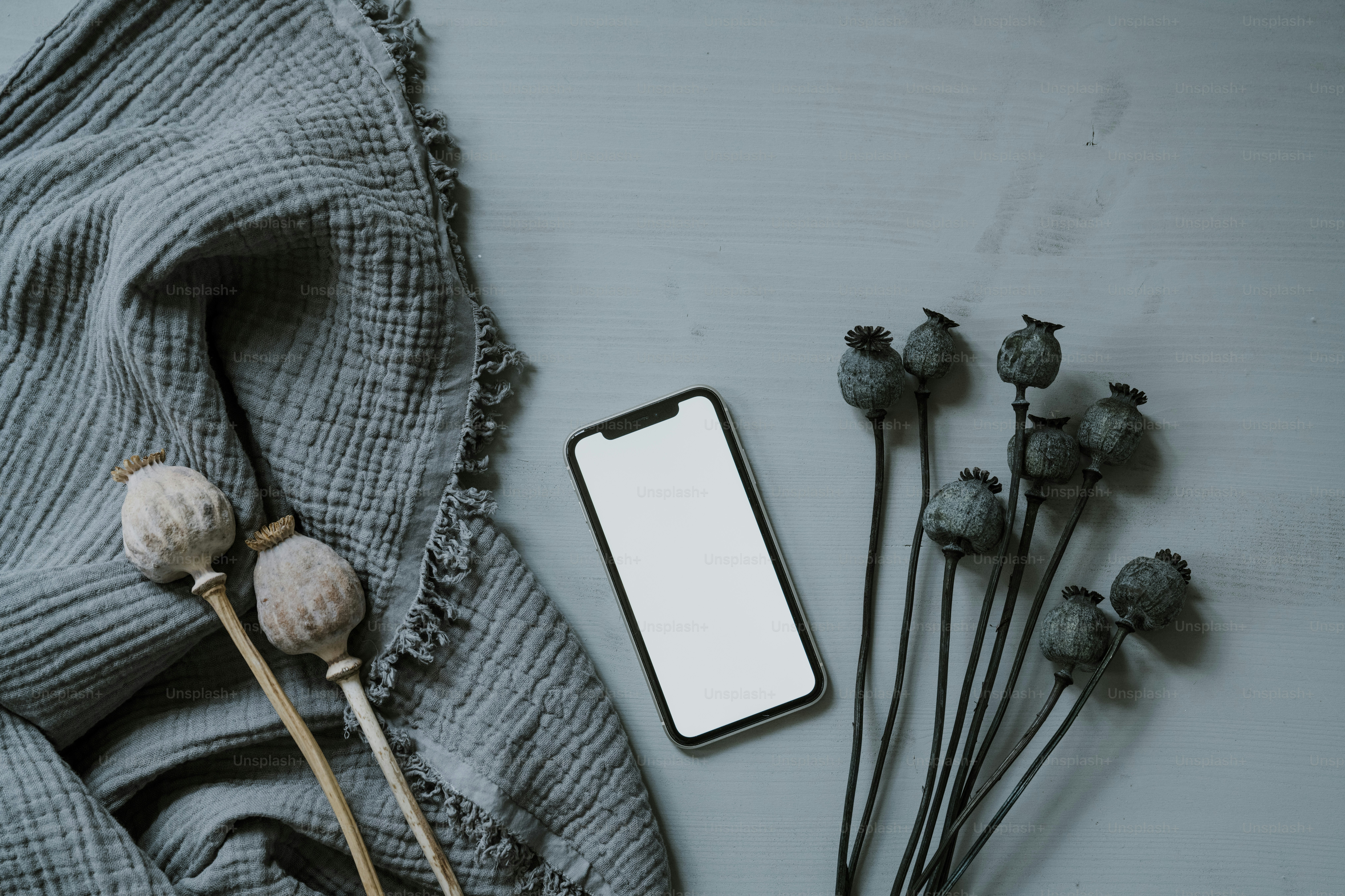 um telefone celular sentado em cima de uma mesa ao lado de flores secas