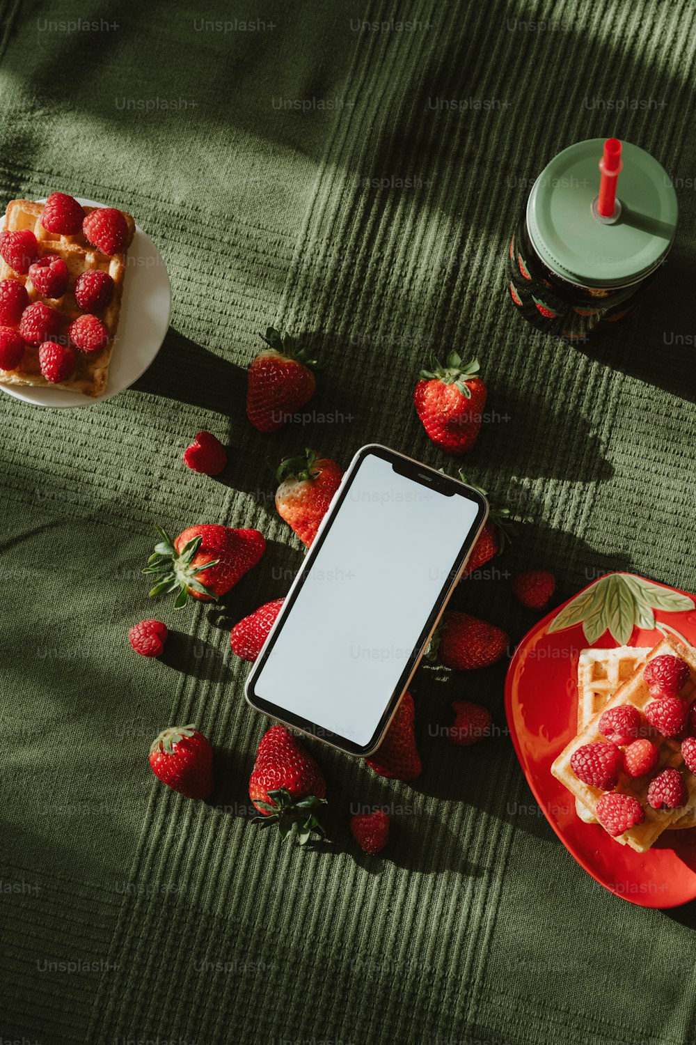 a table topped with a plate of strawberries and a plate of waffles