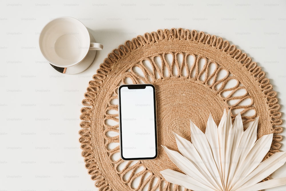 um telefone celular sentado em cima de uma mesa ao lado de uma xícara de café