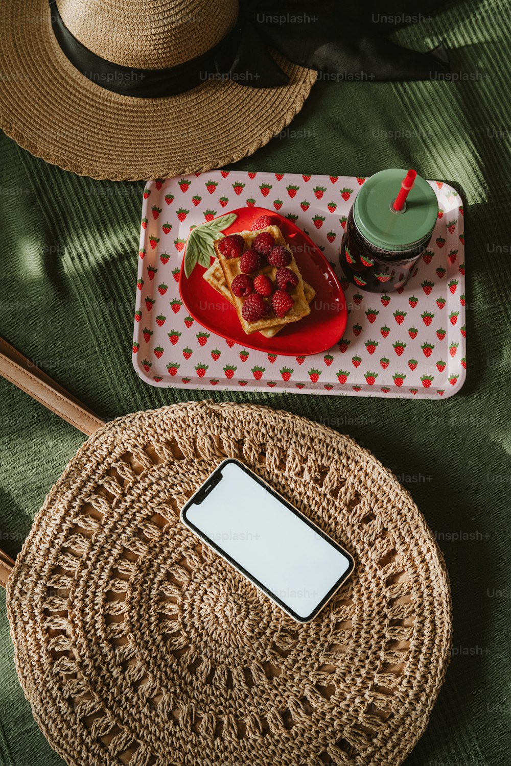 a straw bag sitting on top of a table next to a cell phone