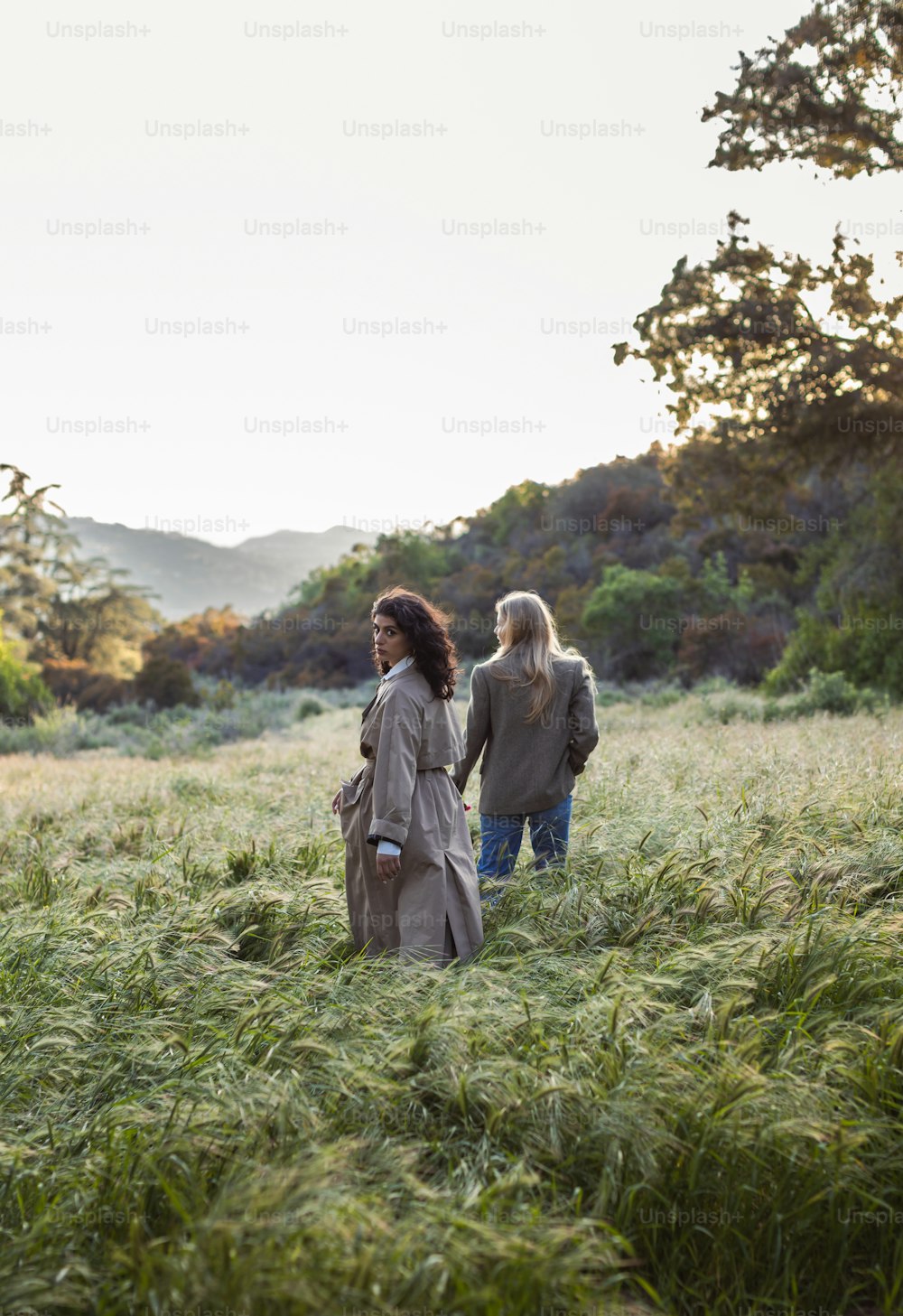 two women walking through a field of tall grass