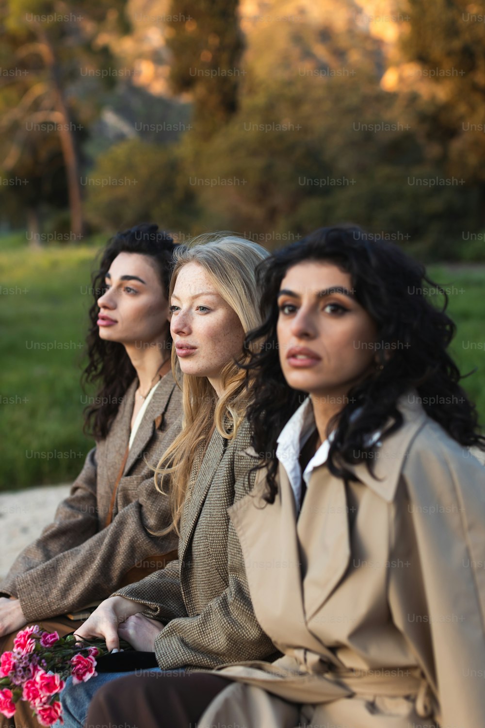 three women sitting on a bench in a park