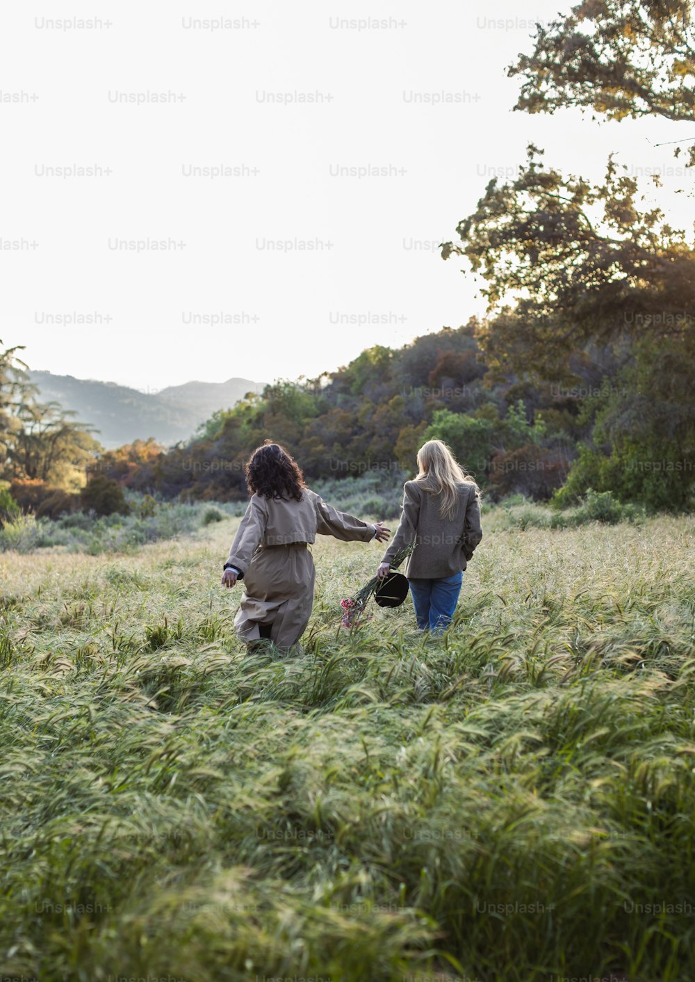 a couple of women walking across a lush green field