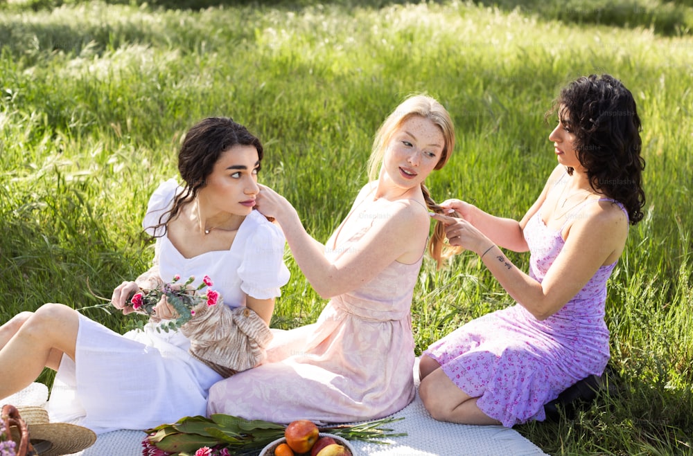 a group of women sitting on top of a grass covered field