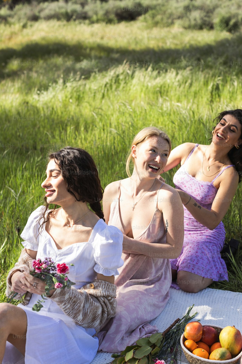 a group of women sitting on top of a grass covered field