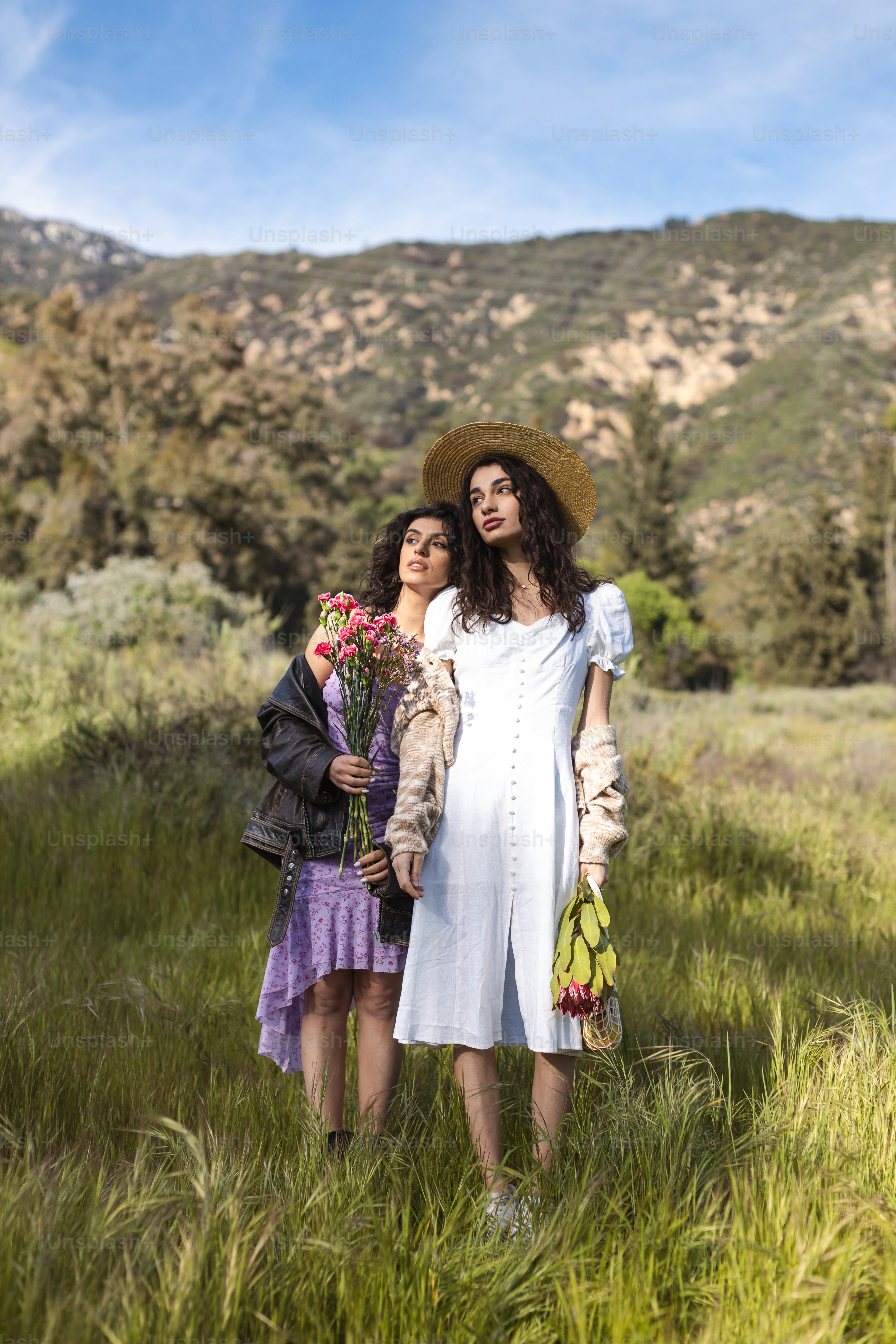 A couple of women standing next to each other in a field photo ...