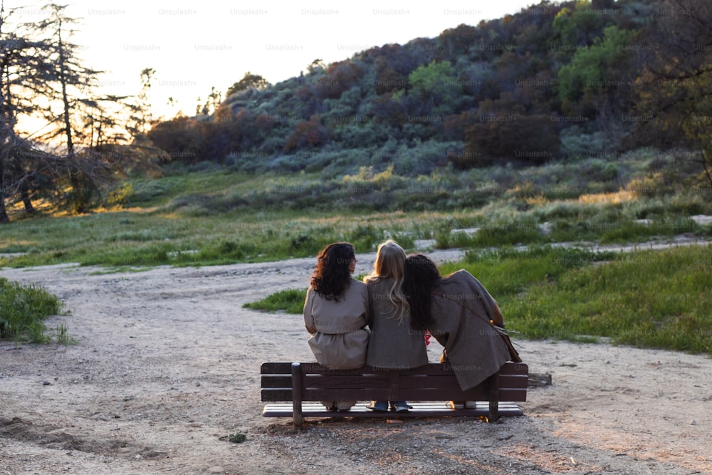 three women sitting on a bench in a park