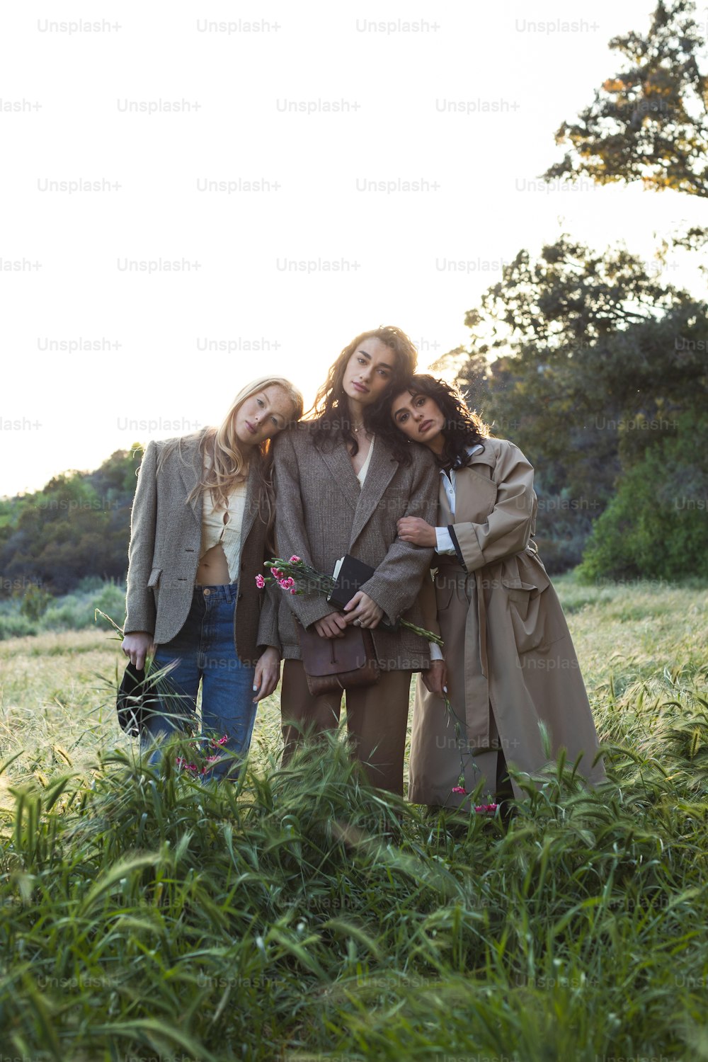 a group of three women standing next to each other in a field