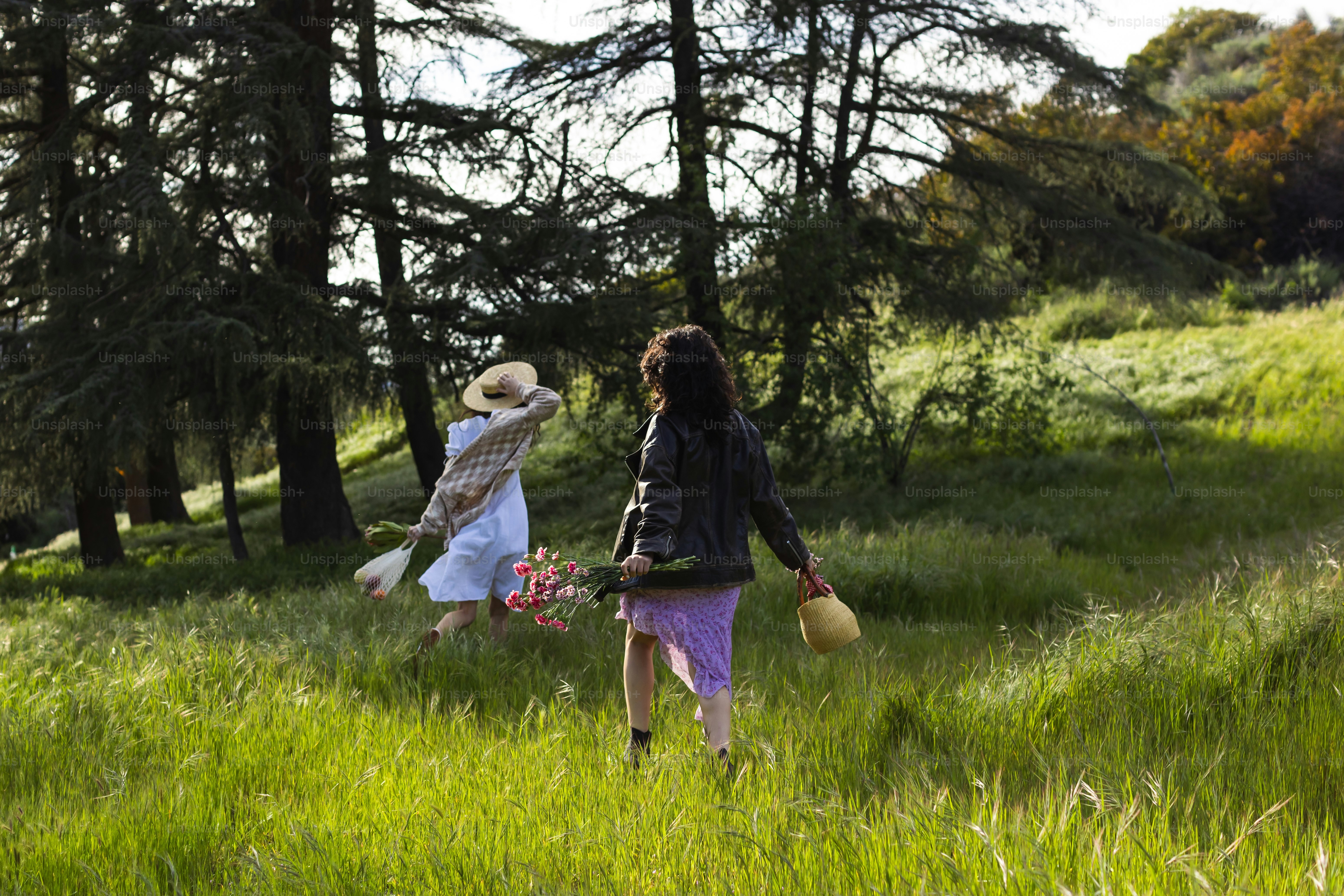 a couple of women walking through a lush green forest