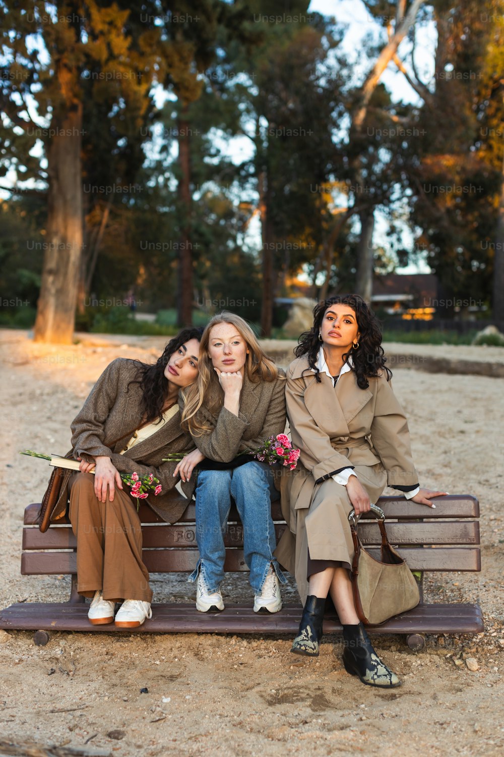 three women sitting on a bench in a park