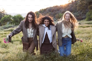 a group of three women walking through a field