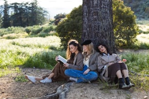 three women sitting on the ground under a tree
