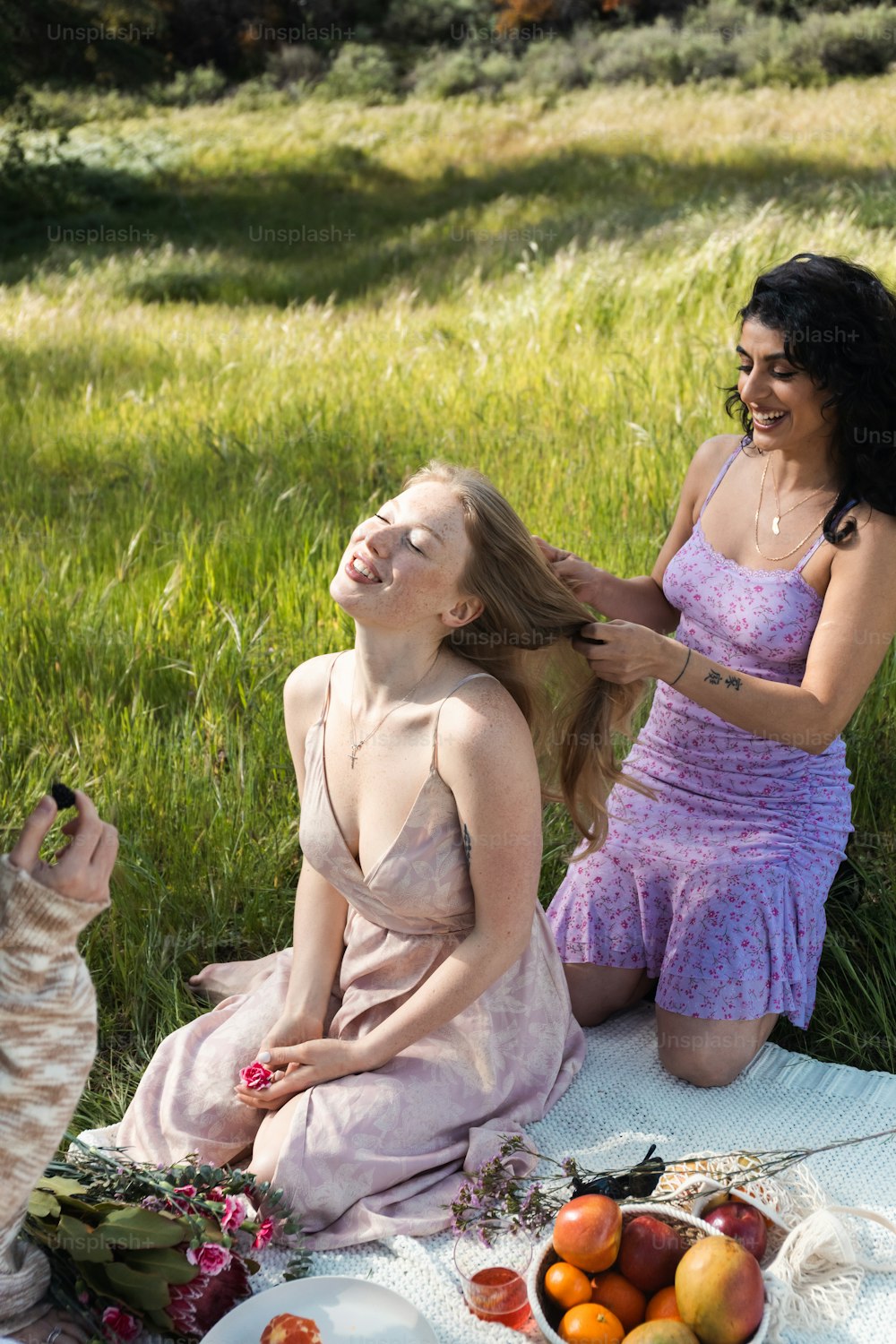 two women sitting on a blanket in the grass