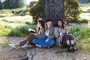 Un gruppo di tre donne sedute accanto a un albero