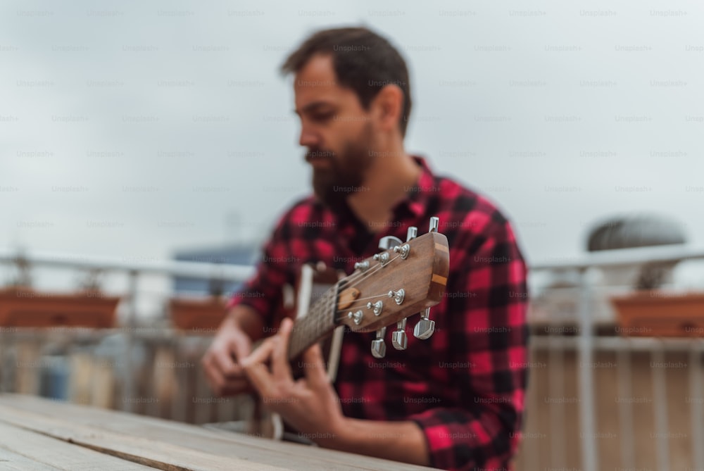 a man playing a guitar on top of a wooden bench