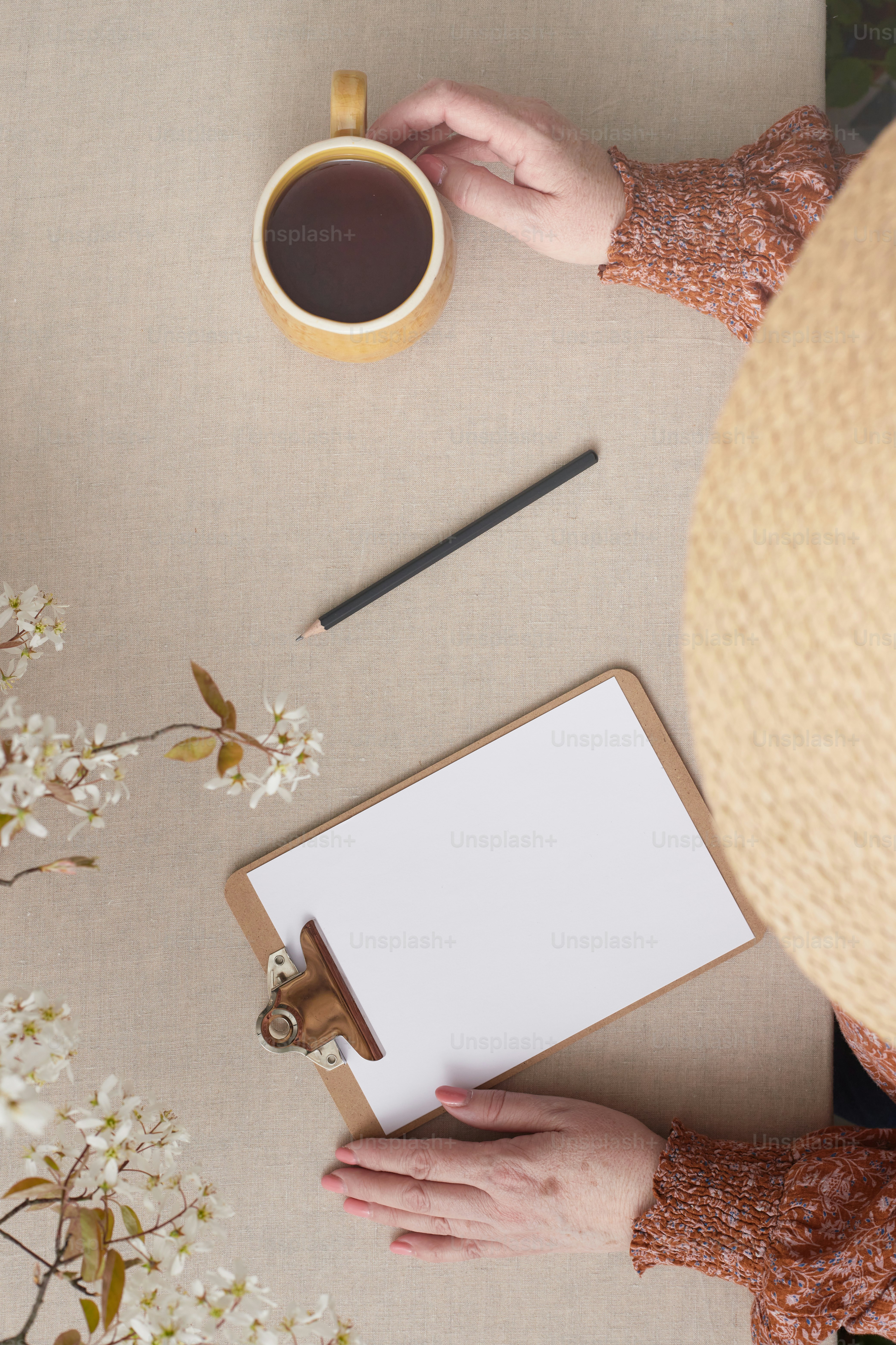 Una persona sosteniendo un portapapeles junto a una taza de café