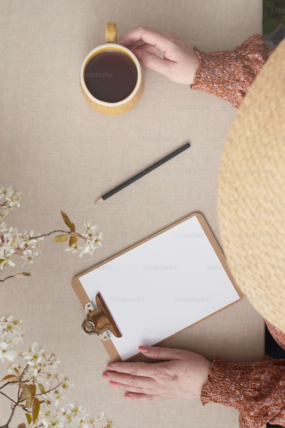 a person holding a clipboard next to a cup of coffee