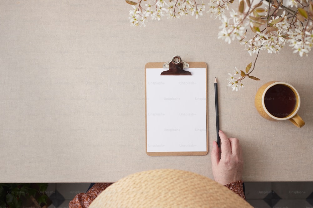 a person holding a clipboard next to a cup of coffee