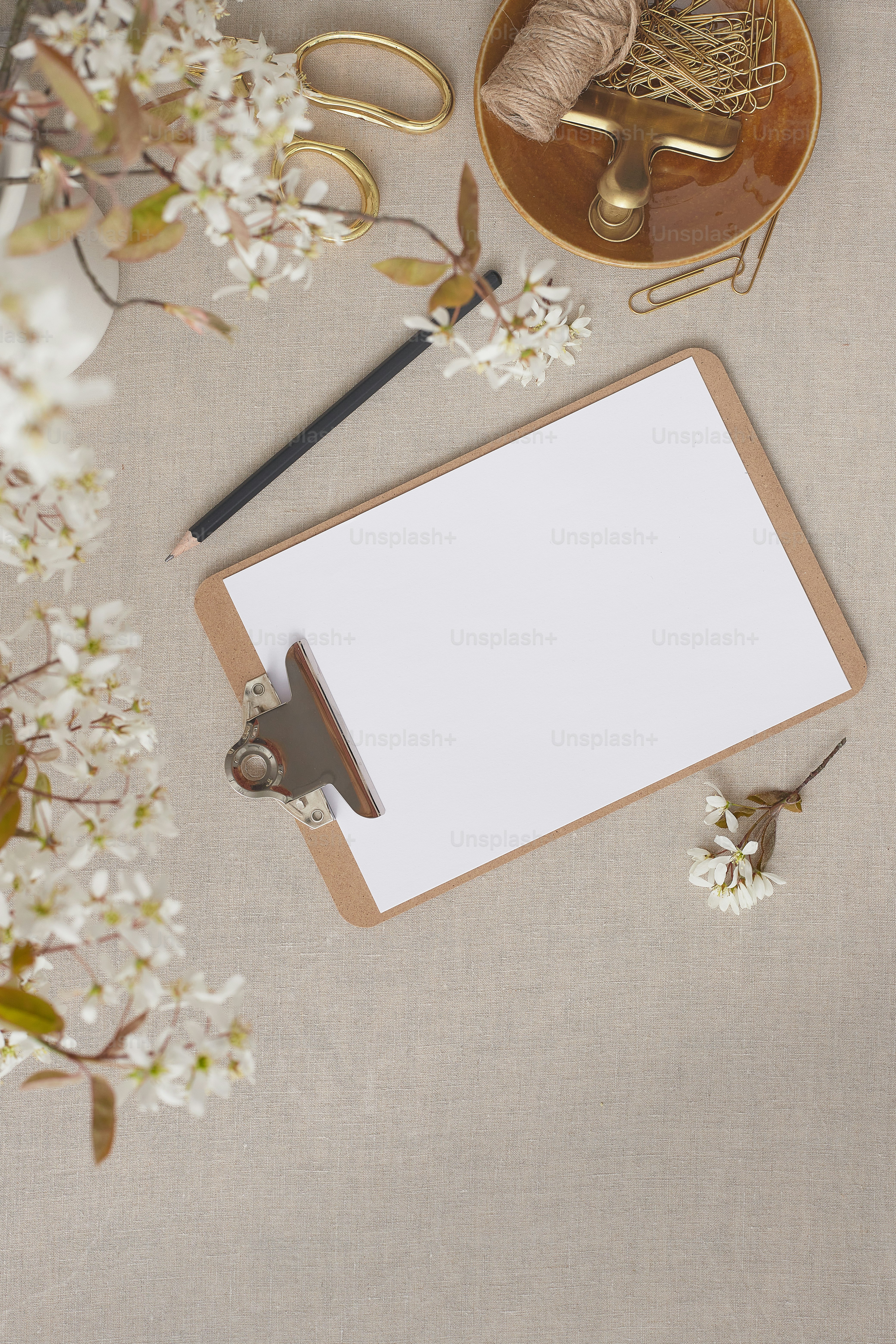 un portapapeles con una hoja de papel blanca junto a un par de tijeras y