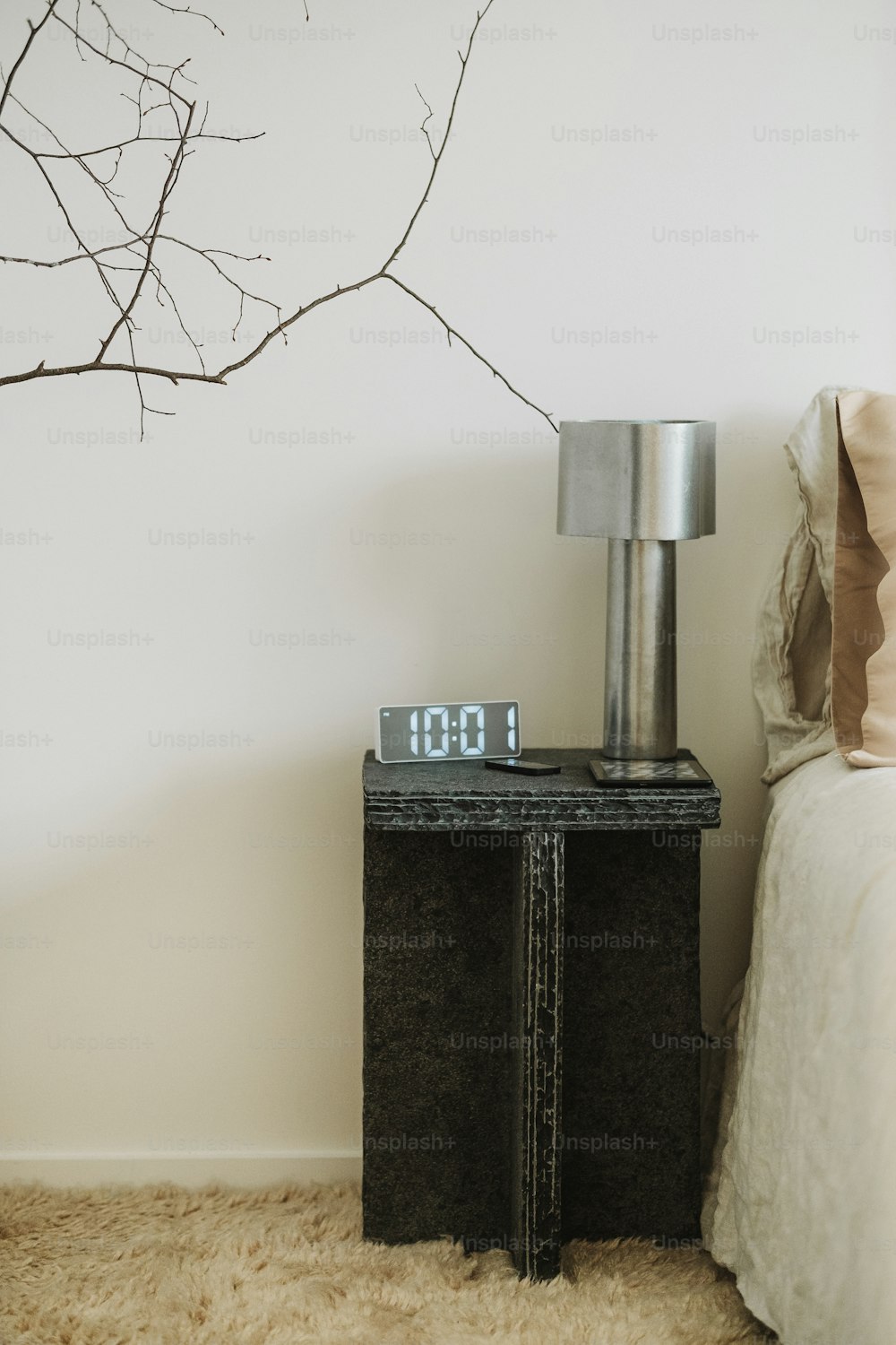 une horloge posée sur une table de chevet à côté d’un lit